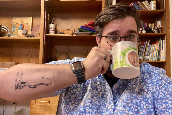 Pastor Ethan is drinking from a "The Hobbit" handmade mug and displaying his then-new tattoo based on The Hobbit.
