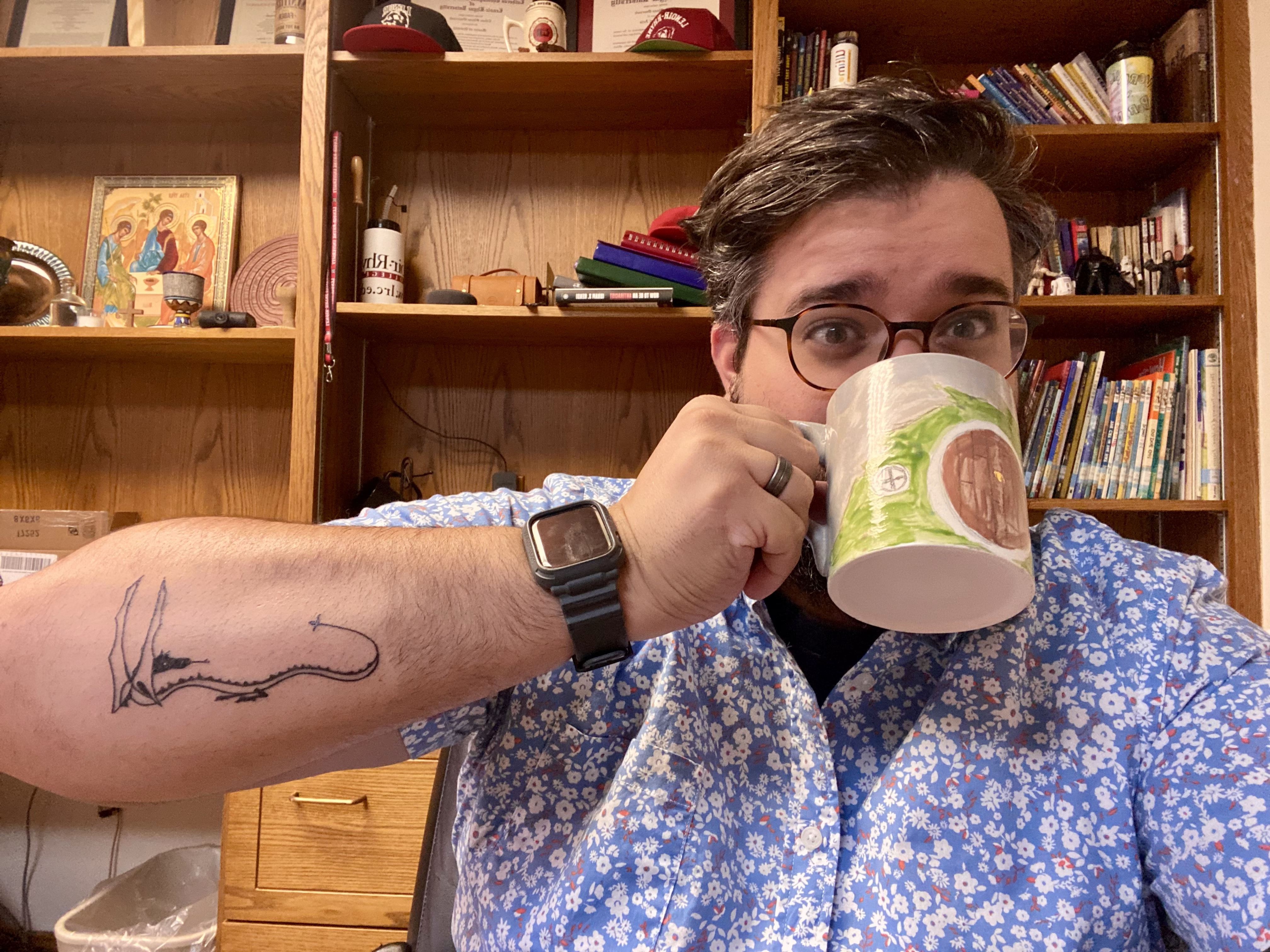 Pastor Ethan is drinking from a "The Hobbit" handmade mug and displaying his then-new tattoo based on The Hobbit.